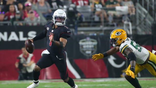 Kyler Murray runs from a defender.